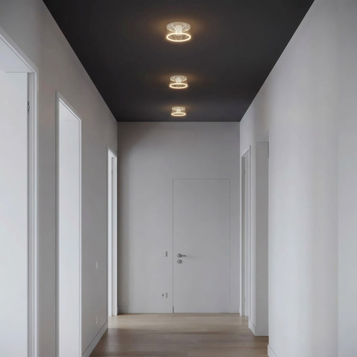 Três lâmpadas LED donut E27 em vidro transparente alinhadas no teto de um corredor sóbrio