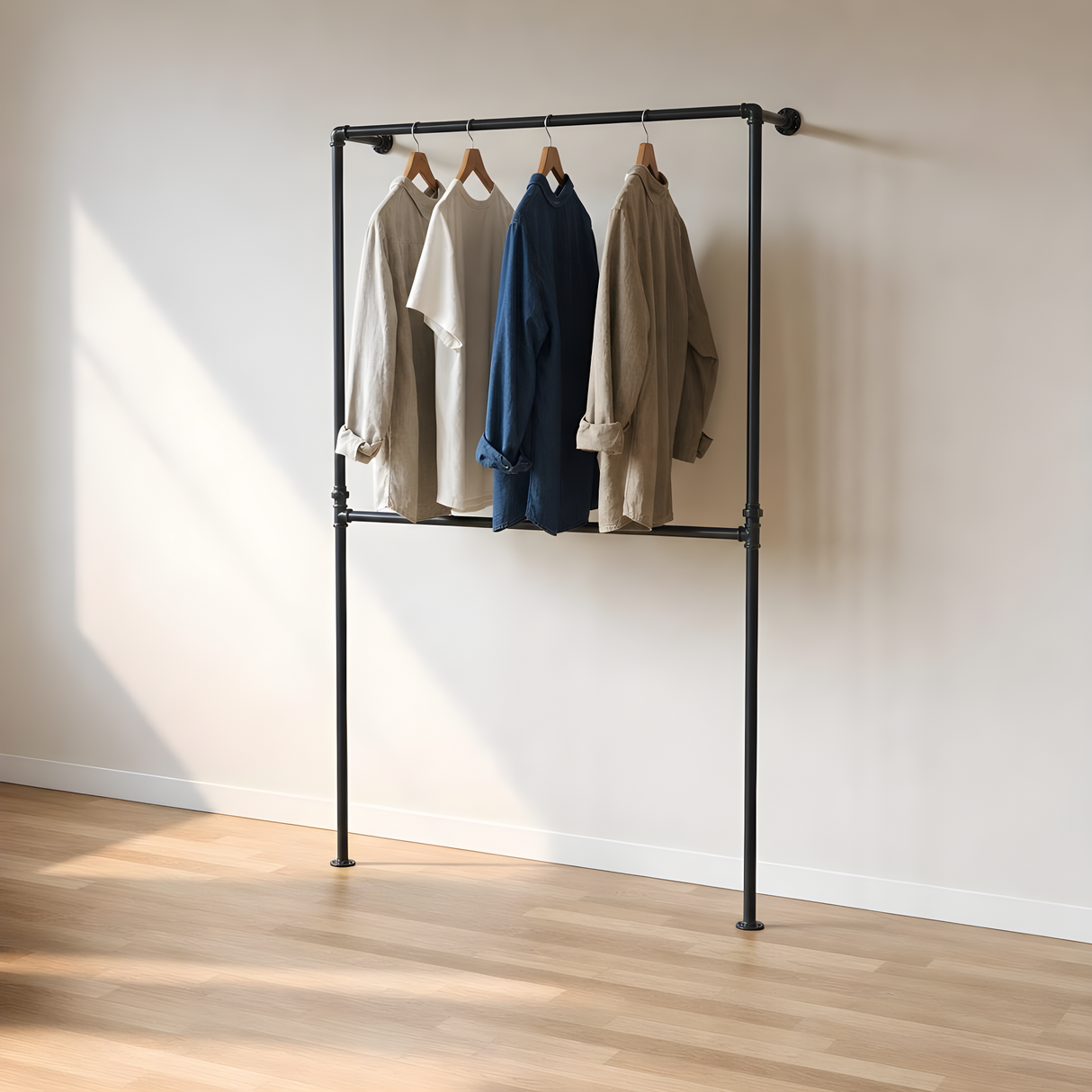 Portant sol-mur double barre en tuyaux noirs fixé au mur, veste et chemises suspendues, lumière naturelle
